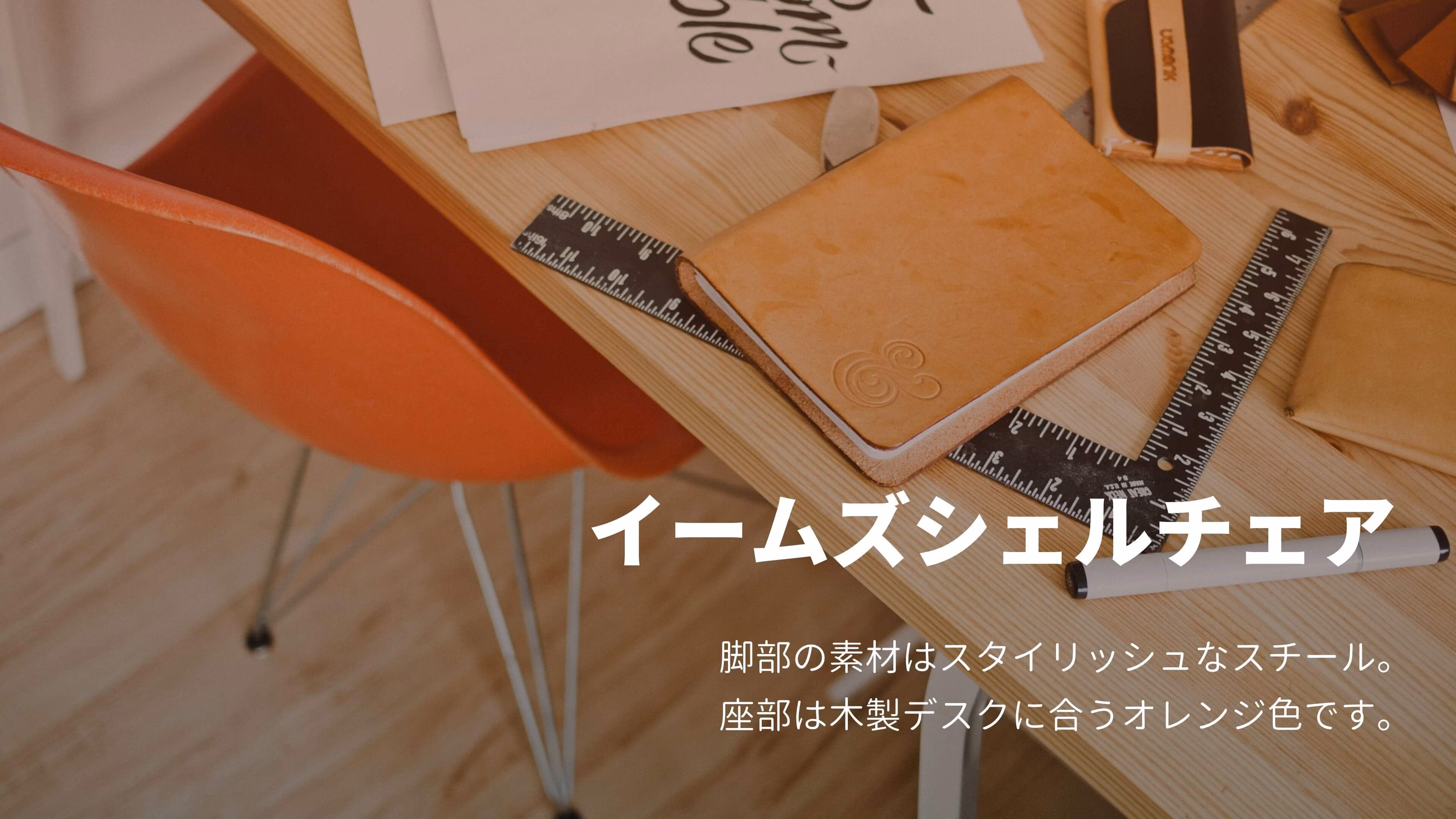 木製デスクと一緒に置かれたスチール製の脚でオレンジ色のイームズシェルチェア